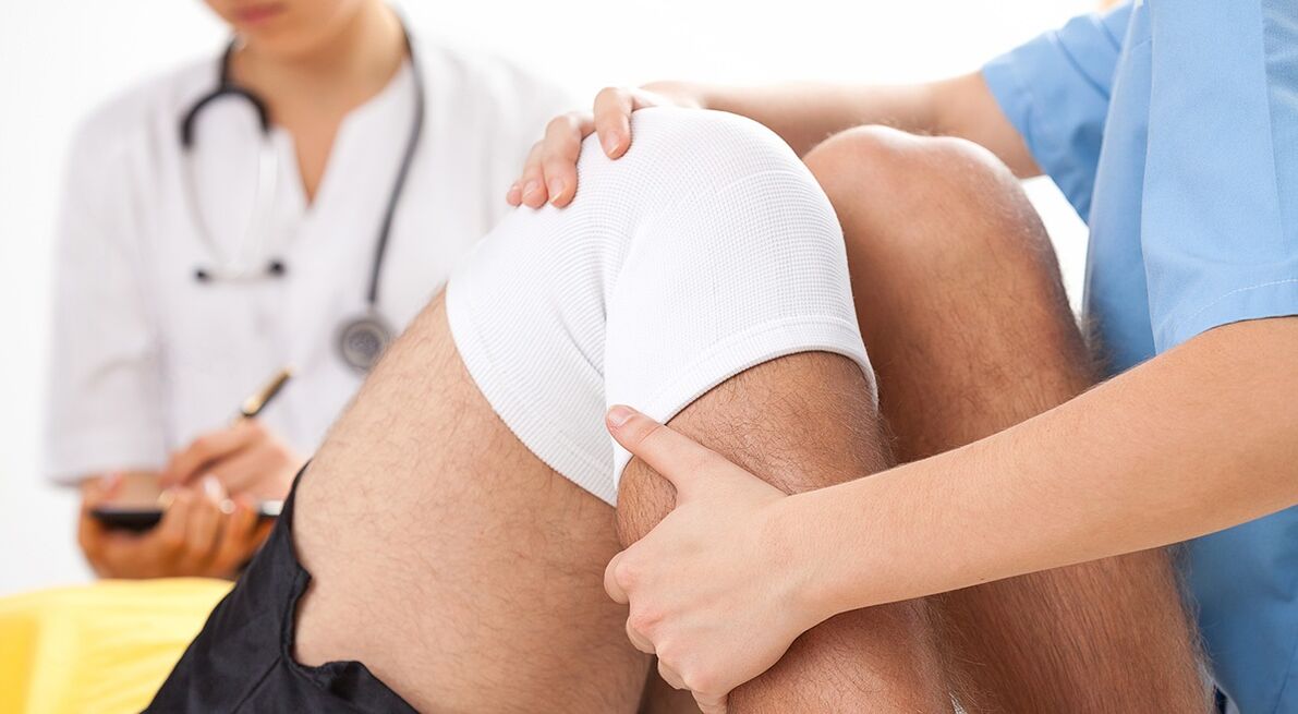 zdravnik, ki pregleda koleno z artrozo